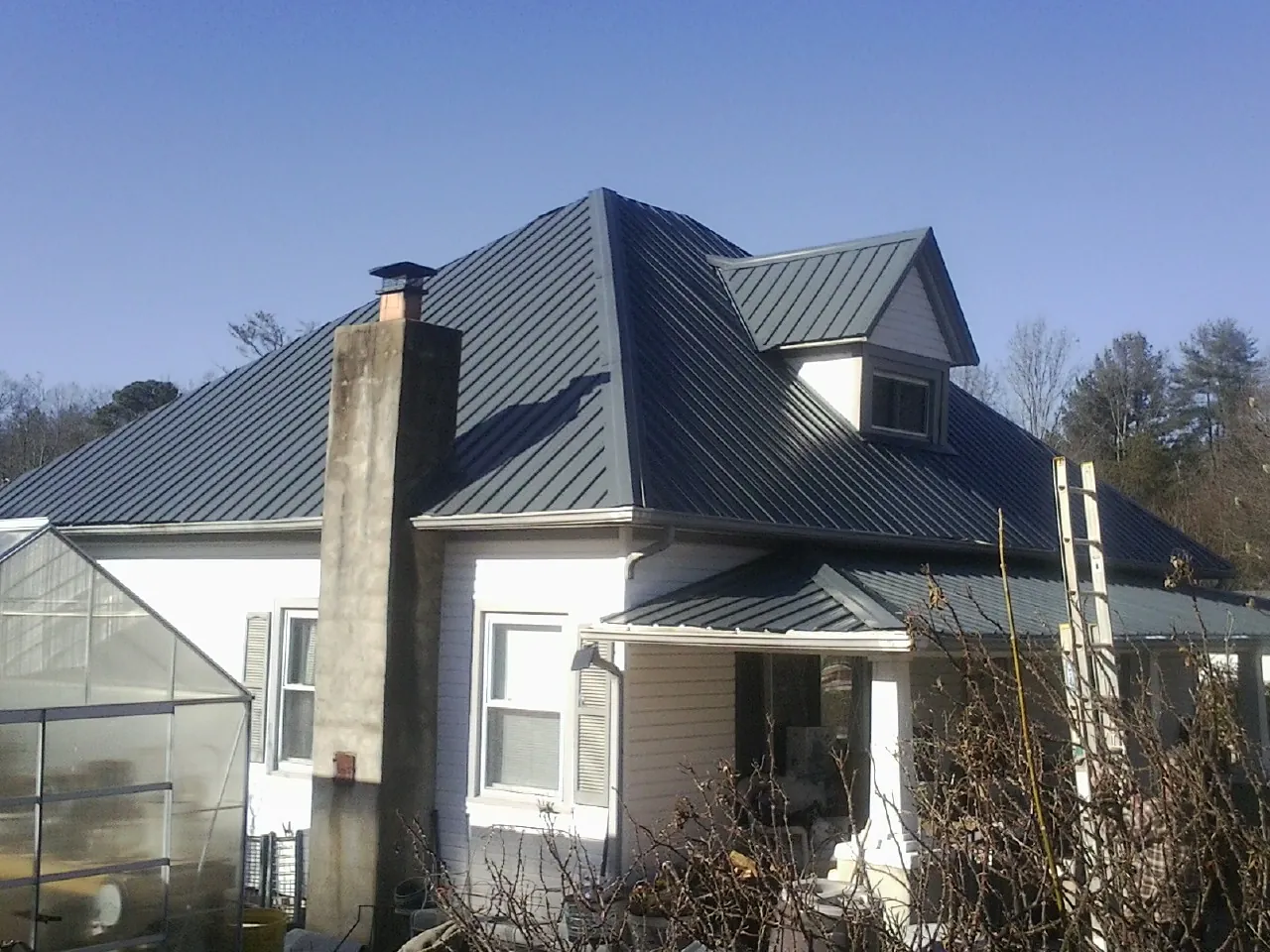 Dark blue standing seam metal roof on a white farmhouse with dormer — Slate & Tile Roof Repair by Roofing Brothers in Red Banks