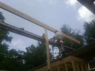 Carpenter setting a ridge beam over a new addition frame — Ice Dam Removal by Roofing Brothers in Red Banks