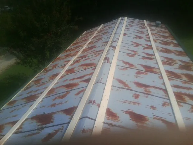Rusted metal roof panels with new wood purlins before replacement — Storm Damage Roof Repair in Red Banks by Roofing Brothers