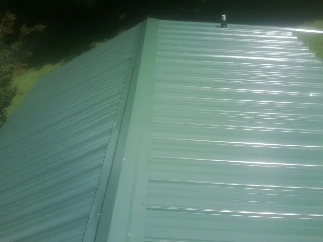 New green metal panels meeting at the ridge of a roof — Flat Roof Repair work by our crew in Red Banks