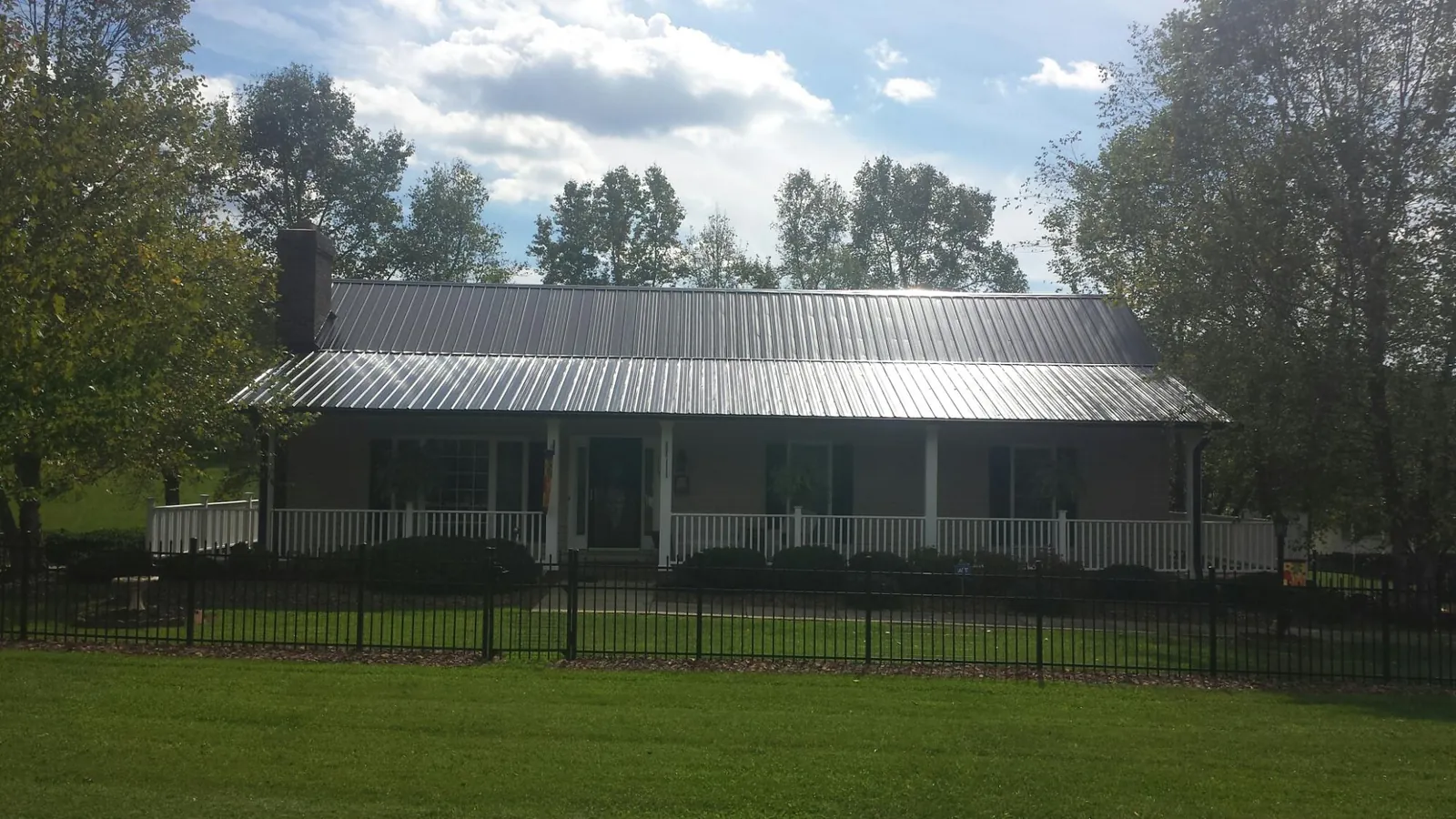 Gray metal roof on a brick ranch with a full width front porch — Gutter Guard Installation work by our crew in Red Banks