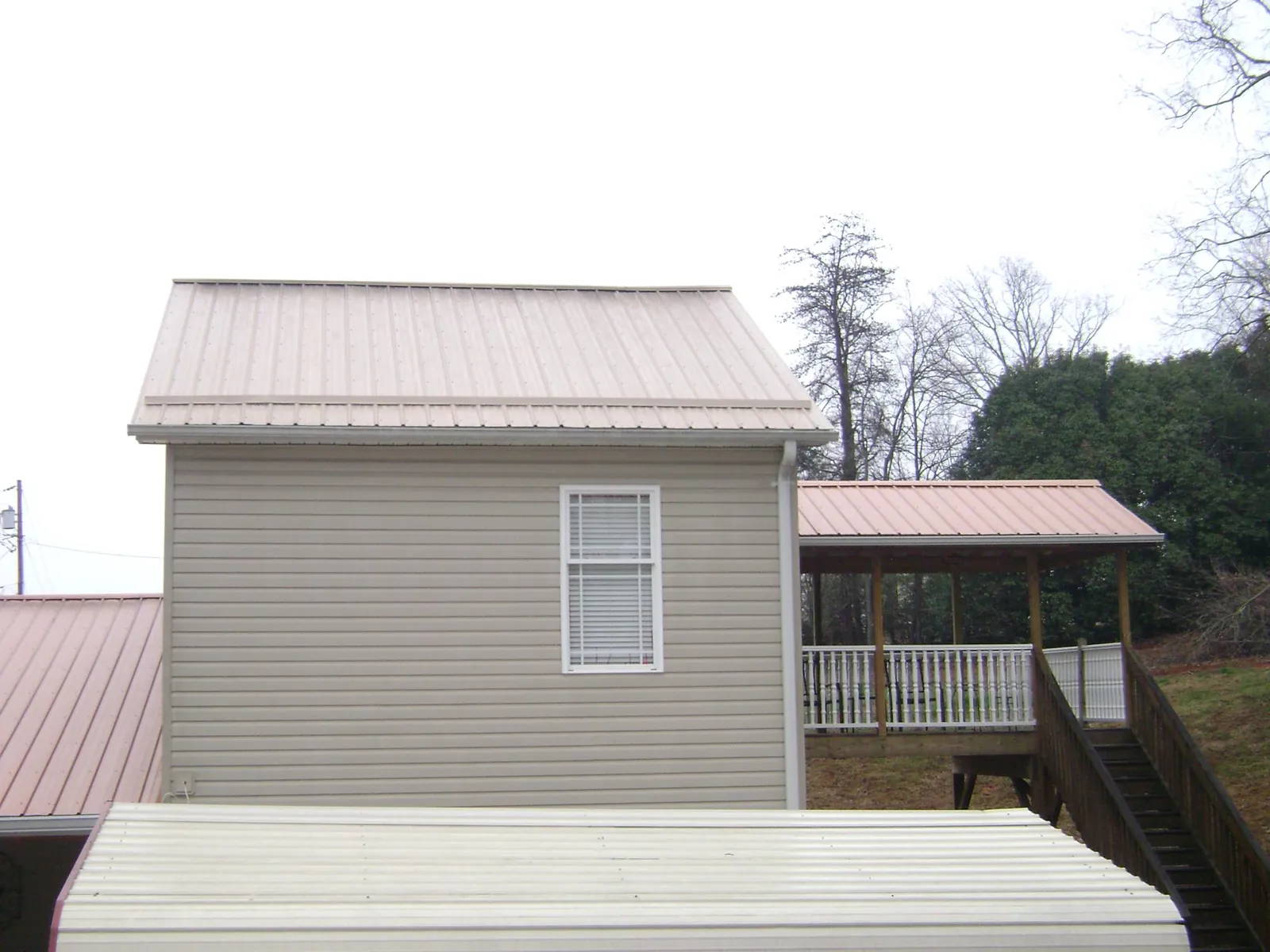 Tan metal roofs on a two story addition and attached porch, from a Roof Replacement job in Red Banks